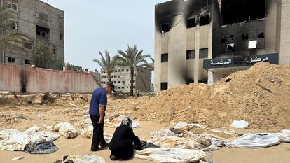 Una mujer y un hombre observan uno de los cuerpos recuperados de la fosa común del hospital Al Nasser, en Jan Yunis, este viernes.