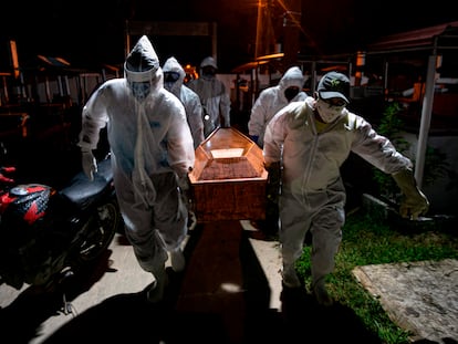 Gravediggers carry the coffin of a victim of the coronavirus for its burial in Breves in the Brazilian state of Para.