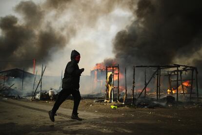 Un migrante corre por 'La Jungla' de Calais durante el tercer día de evacuaciones. 