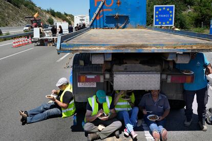 Varias personas descansan bajo un vehículo, mientras la AP-7 se encuentra completamente cerrada al tráfico en dirección a Francia por las protestas convocadas este lunes.
