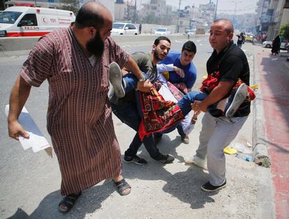 Palestinos llevan a un manifestante herido durante enfrentamientos con las fuerzas de seguridad israelíes en el control de Qalandiya, entre Ramala y Jerusalén.