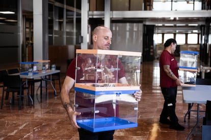 Operarios municipales trabajan en el montaje del colegio electoral para el 23-J en el vestíbulo de la sede del Ayuntamiento de Barcelona.