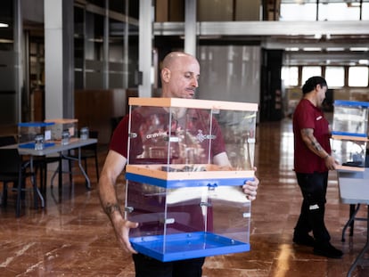 Operarios municipales trabajan en el montaje del colegio electoral para el 23-J en el vestíbulo de la sede del Ayuntamiento de Barcelona.