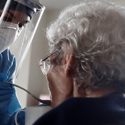 Una cuidadora ayuda a comer a una anciana en una residencia del barrio madrileño de Villaverde, en Madrid.