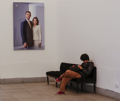 Un visitante espera en una de las salas preparadas para recibir a los turistas en el Palacio Real. Un cuadro de la imagen de los Reyes de España decora sus paredes.