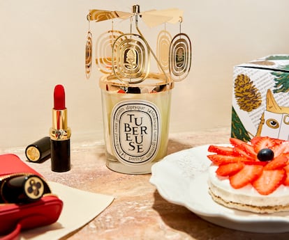 Neceser Nice Beauty en piel Épi y barras de labios mate LV Rouge, todo de LOUIS VUITTON; vela Tubéreuse y carrusel decorativo dorado, ambos de DIPTYQUE. Tarta para dos de BRELA BAKERY y plato de MAISONS DU MONDE.