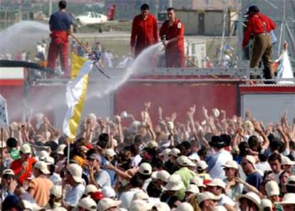 Los bomberos riegan con agua a los asistentes al evento católico.