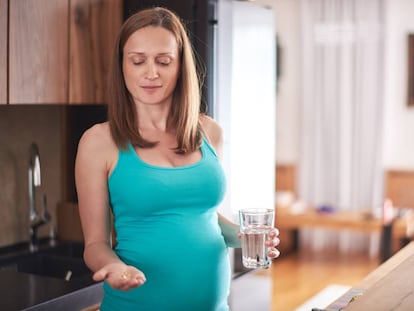 Mujer embarazada toma pastilla. 