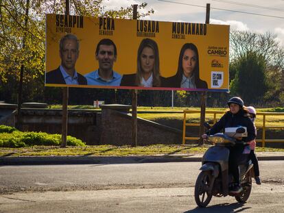 Un motociclista circula frente a propaganda electoral, en Santa Fé, Argentina.