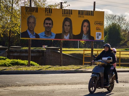 Un motociclista circula frente a propaganda electoral, en Santa Fé, Argentina.