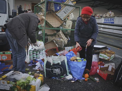 Dos personas recogen comida de la basura en Madrid, en diciembre de 2019.