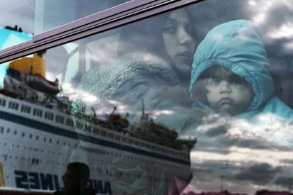 Una mujer y su hijo miran a través de la ventana del autobús donde se refleja el ferry del que desembarcaron, en el puerto de El Pireo en Atenas (Grecia). Cerca de 850.000 migrantes han entrado en la Unión Europea este año desde Grecia.
