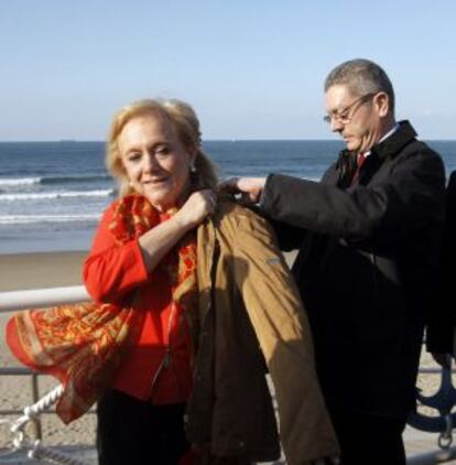 Gallardón ayuda a ponerse el abrigo a la candidata del PP en Asturias, Mercedes Fernández, durante un paseo por el municipio de Salinas.