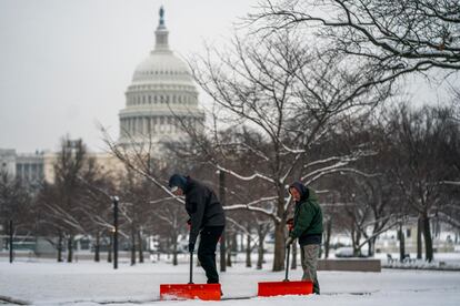 Groundskeepers shovel the sidewalk at the National Gallery of Art near the US Capitol following the first snowfall of the year in Washington, DC, USA, 16 January 2024.