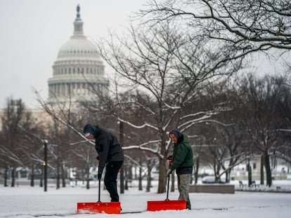 Groundskeepers shovel the sidewalk at the National Gallery of Art near the US Capitol following the first snowfall of the year in Washington, DC, USA, 16 January 2024.