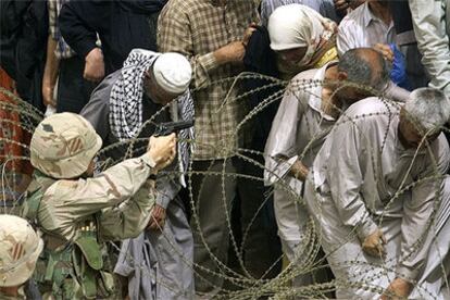 Un soldado estadounidense intenta controlar una cola de pensionistas iraquíes en Bagdad.