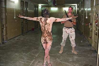 Un preso iraquí, desnudo y cubierto por una sustancia ocre, ante un soldado de EE UU con una porra en Abu Ghraib.