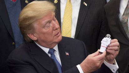 Trump mira a un muñeco con forma de astronauta durante la firma de la directiva.