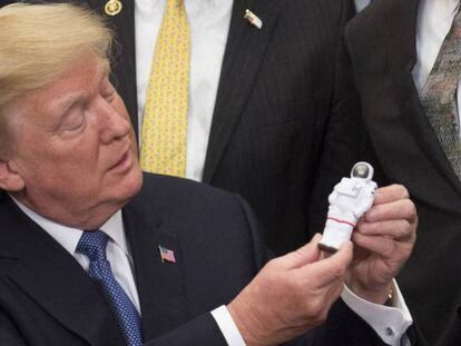Trump mira a un mu&ntilde;eco con forma de astronauta durante la firma de la directiva. 
