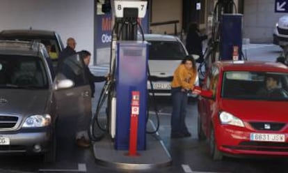 Clientes de una gasolinera poniendo combustible tras la bajada de precios. 