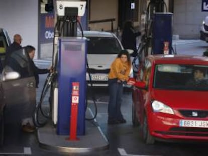 Clientes de una gasolinera poniendo combustible tras la bajada de precios. 