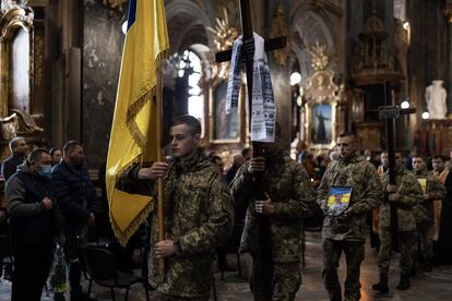 Un grupo de soldados caminan con la bandera de Ucrania en la iglesia católica de los Santos Apóstoles Pedro y Pablo, durante el entierro de dos soldado muertos durante un ataque aéreo ruso en la ciudad de Mykolaiv, el de marzo de 2022.