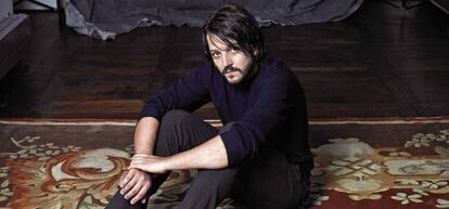 Diego Luna vestido con un jersey azul de Cos, pantalón Giorgio Armani y botas Tod's.