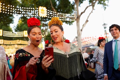 La Feria es el principal evento económico de la ciudad, ya que supone el 3% del PIB de la capital andaluza. En la imagen, dos mujeres consultaban un teléfono móvil, el domingo en el recinto ferial.