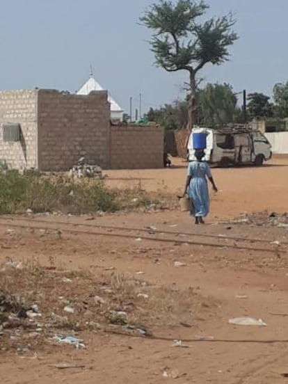 Mulher caminha com balde d'água na cabeça em Dahra, Senegal.