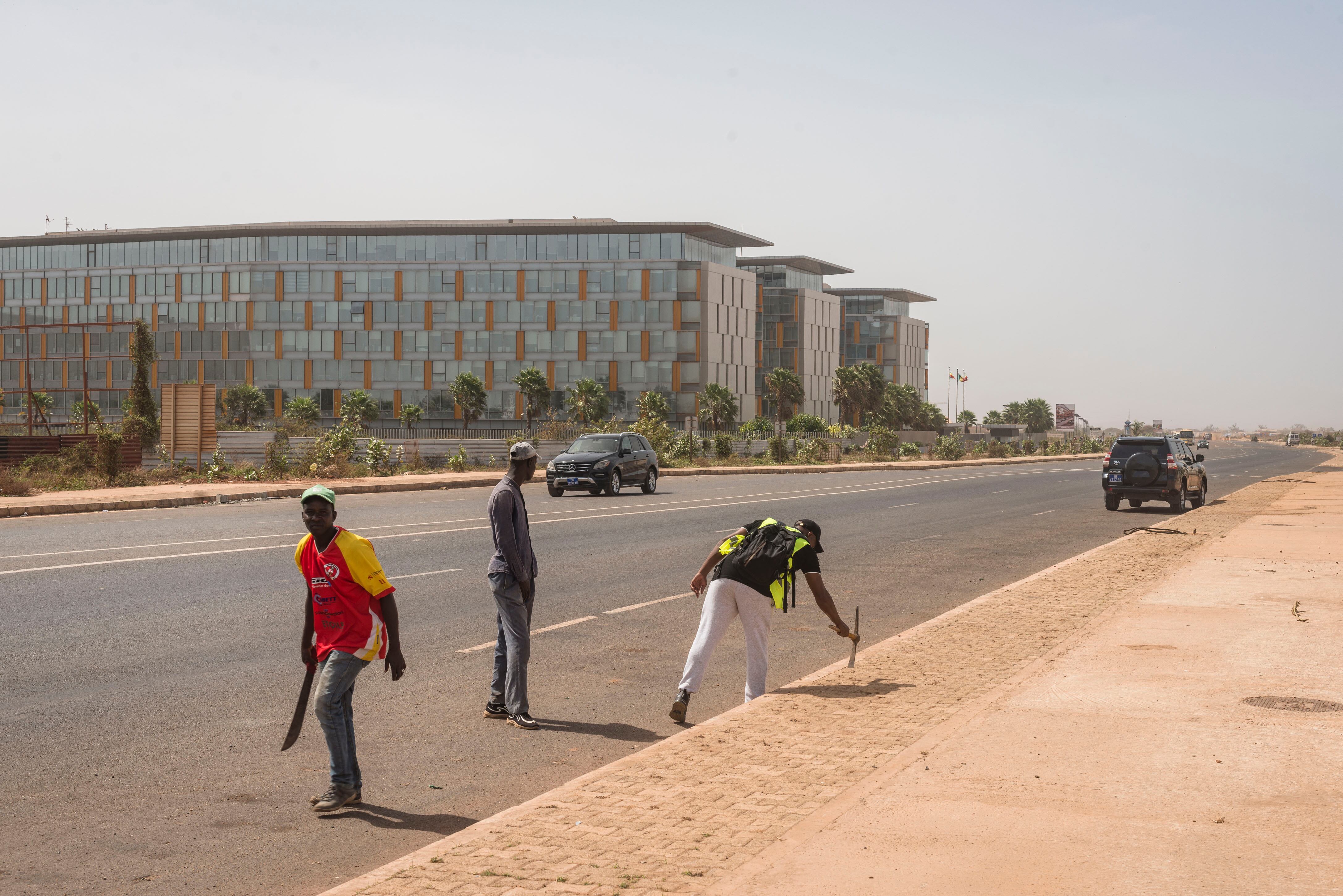 Tres trabajadores retocan las aceras del barrio de Diamniadio, el pasado mes de mayo. En solo cinco años, una nueva ciudad ha ido emergiendo en medio de la nada a 30 kilómetros de Dakar. 