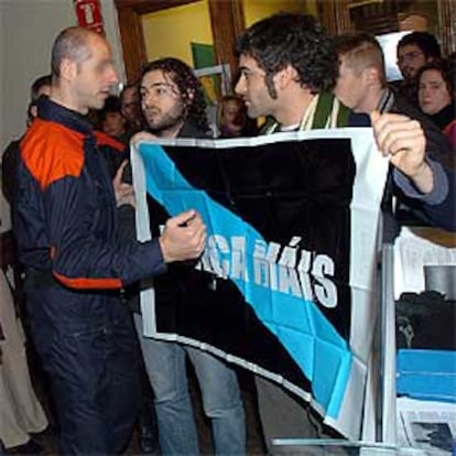 Un agente de la Ertzaintza habla con los jóvenes que portan una pancarta de Nunca Máis.