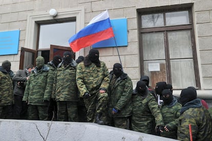 Homens mascarados seguram uma bandeira russa enquanto bloqueiam um edifício do governo na região autônoma ucraniana da Crimeia.