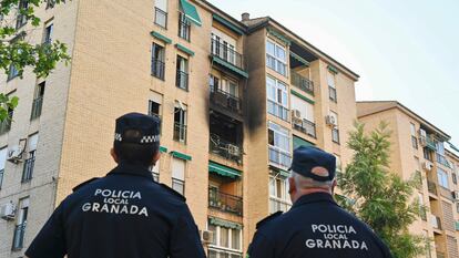 Dos policías frente al inmueble en el que se ha producido el incendio, en la calle Circunvalación del barrio de la chana, en Granada este lunes.