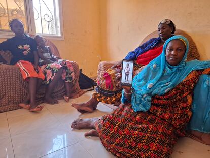 Fagueye Sylla, tía de Daba Diop, muestra la foto de su sobrina fallecida en un cayuco el pasado 8 de septiembre. Detrás, Ndeye Awa Sylla, madre de la joven, junto a las dos hijas de Daba Diop, en su casa familiar de Mbour.