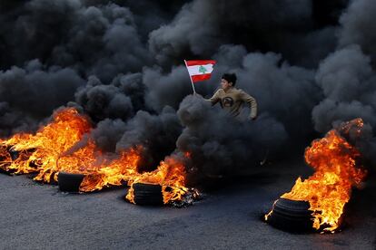 Un manifestante salta sobre unos neumáticos en llamas, en una autovía del norte de Beirut (Líbano). 