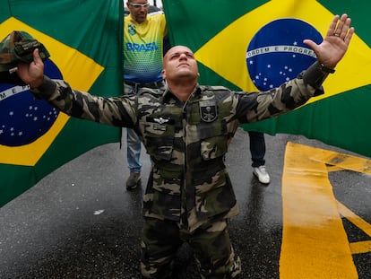 Jair Bolsonaro supporter wearing military clothes, kneeling in front of two Brazilian flags during Rio De Janeiro protests