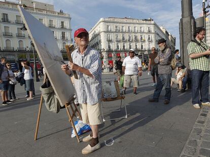El pintor manchego Antonio López, en la Puerta del Sol trabajando en un lienzo sobre la Casa de Correos.