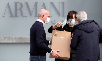 Trabajadores reparten mascarillas en el exterior del teatro donde el diseñador Giorgio Armani tenía previsto realizar su desfile en Milán, este domingo.