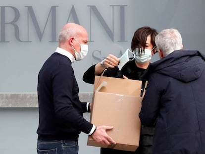 Trabajadores reparten mascarillas en el exterior del teatro donde el diseñador Giorgio Armani tenía previsto realizar su desfile en Milán, este domingo.