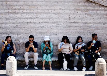 Varios turistas se sientan a la sombra para evitar el calor, este martes en Roma. 