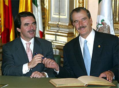 El presidente mexicano Vicente Fox le presta un bolígrafo a Jose María Aznar después de firmar el libro de honor de la Casa de América.