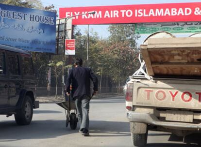 Un hombre trata de sortear el tráfico con su carretilla en una avenida de Kabul.