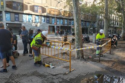 Dos operarios vallan una zona deteriorada tras los disturbios de los últimos días en Barcelona.