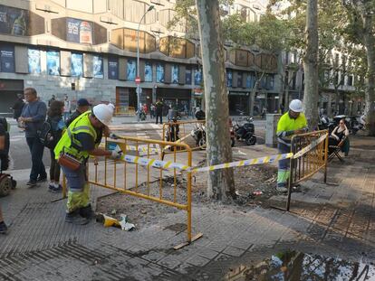 Dos operarios vallan una zona deteriorada tras los disturbios de los últimos días en Barcelona.