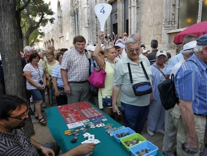 Un grupo de cruceristas pasa frente a un puesto de numism&aacute;tica tras visitar la Lonja de Valencia.