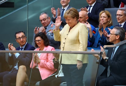 The German former chancellor, Angela Merkel, greets from the guest tribune.