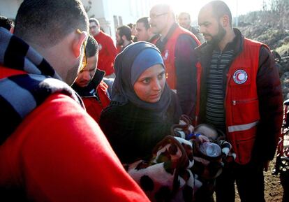 Una mujer siria con un niño entre trabajadores de la Media Luna Roja, organización que ayuda a la evacuación de civiles de la ciudad de Homs.  