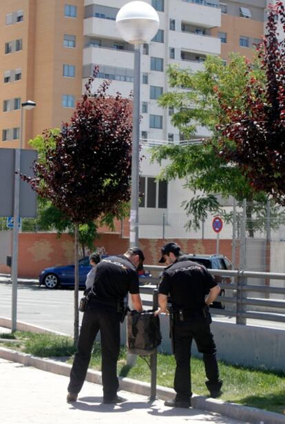 Dos policías miran en una papelera cerca del lugar del crimen.