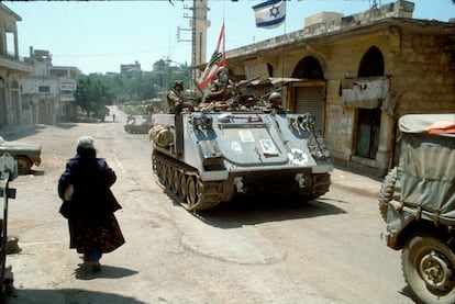 Una mujer pasa junto a un convoy de tropas israelíes que atraviesan un pueblo del valle de la Becá tras la invasión de Líbano, el 6 de junio de 1982.