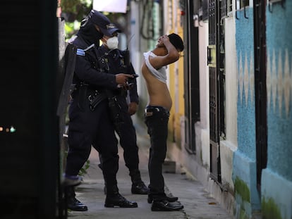A police officer searches a man in Soyapango, El Salvador